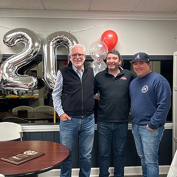 Three friends joyfully celebrate a 20th anniversary in a festive, cozy gathering.