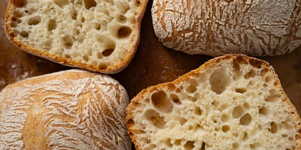 Sliced artisan bread loaves displaying open crumb structure and airy texture, ideal for wholesale food distribution and commercial bakery supply.