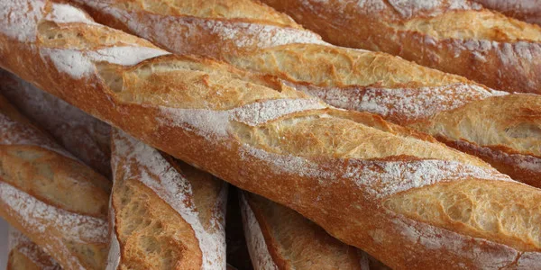 Stack of freshly baked French baguettes with crispy golden crust and flour dusting, ideal for foodservice distribution.