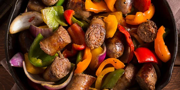 Seasoned beef meatballs cooked with colorful bell peppers, onions, and green peppers in a commercial skillet for foodservice.