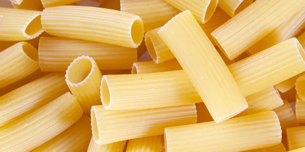 Close-up of uncooked rigatoni and penne pasta tubes in bulk, ideal for food distributors, manufacturers, and commercial foodservice suppliers.