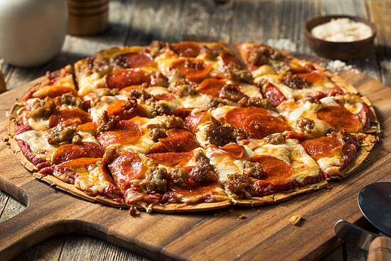 Irresistible pepperoni pizza on a wooden peel, showcasing melted cheese and rich toppings.