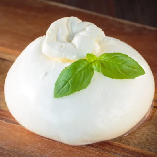 Professional plated white mousse dessert topped with whipped cream and fresh basil leaves on a wooden surface, ideal for fine dining food service.