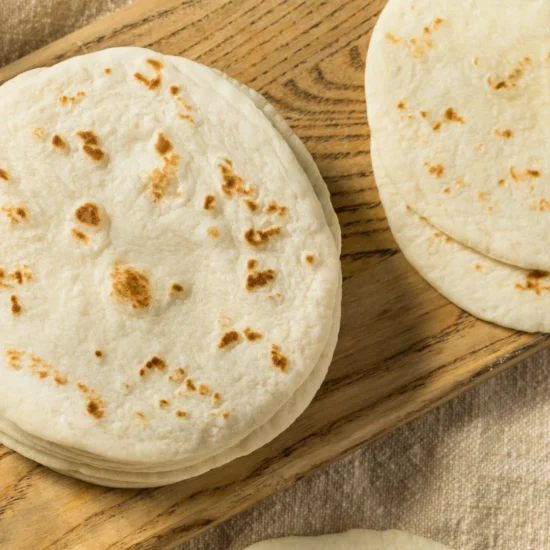 Stack of freshly made flour tortillas with char marks, ideal for wholesale food suppliers and commercial foodservice distribution.