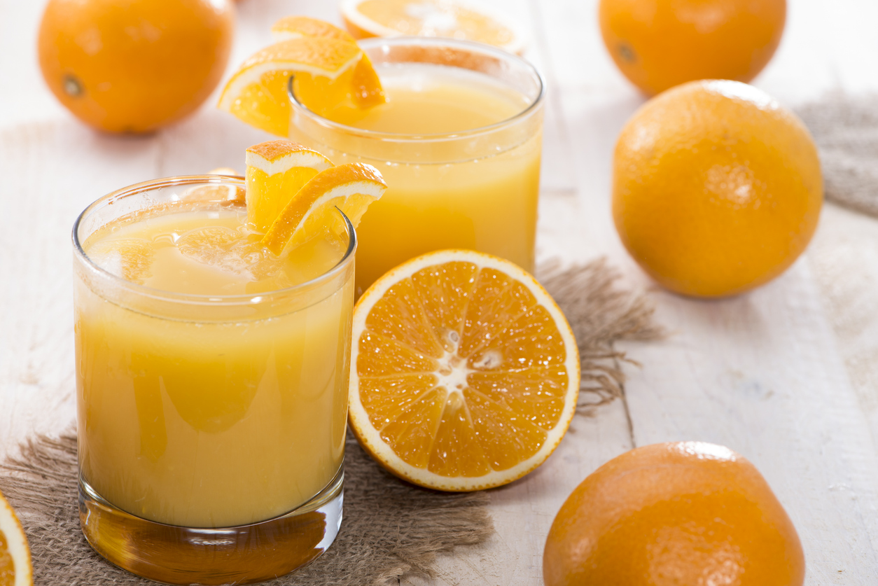 Refreshing orange juice served in elegant glasses, surrounded by fresh oranges on rustic wood.