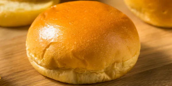 Fresh golden burger buns with glossy finish, ideal for wholesale food suppliers and commercial foodservice operations.