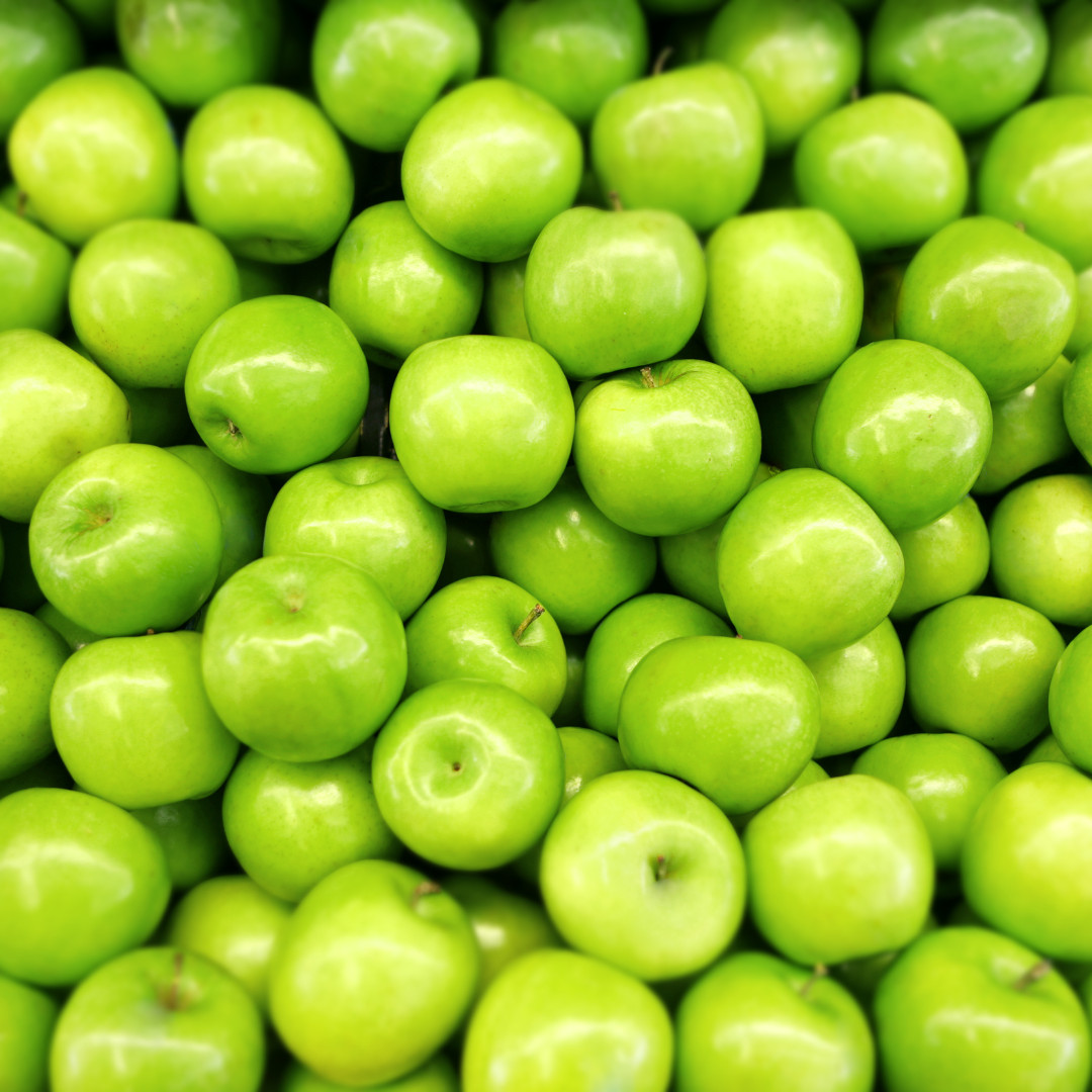 Close-up of shiny green apples, showcasing freshness and organic charm in vibrant clusters.
