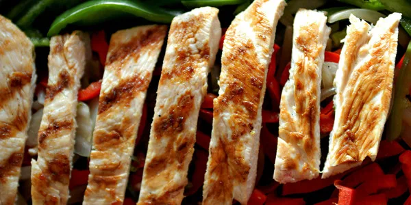 Golden-brown grilled chicken breast strips arranged in rows, ideal for wholesale food distribution and commercial food service operations.
