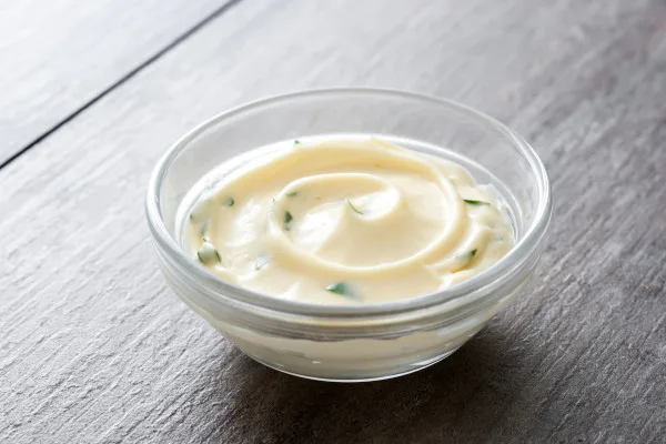 Creamy herb-infused sour cream dip in clear container with fresh chive garnish, ideal for wholesale food distribution and foodservice applications.