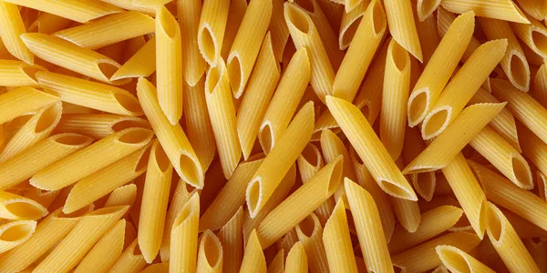 Close-up of dry penne pasta tubes, ideal for food service suppliers, distributors, and wholesale food manufacturers.