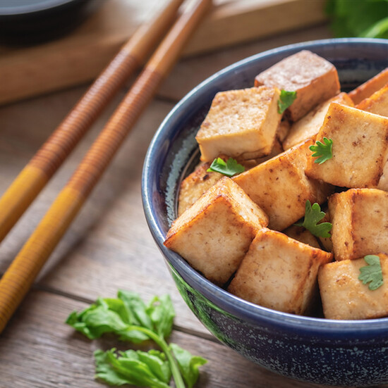 Golden-brown fried tofu with cilantro in a blue ceramic bowl, perfect for Asian-inspired meals.